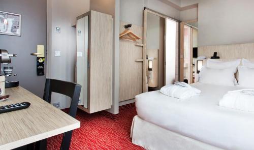 a hotel room with a large white bed and a desk at Libertel Gare Du Nord Suede in Paris