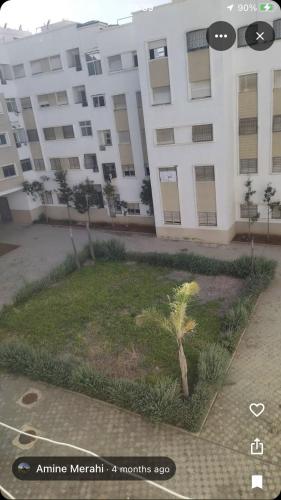 a large white building with a palm tree in front of it at Zen and cosy Appart Rose Marie Kasbah in Skhirat