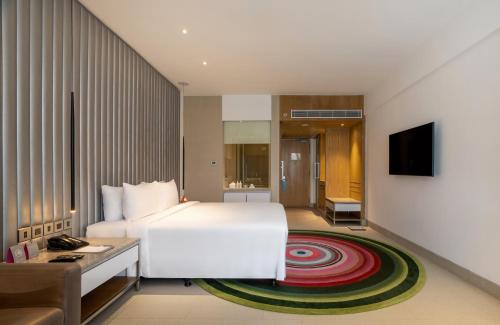 a hotel room with a white bed and a television at Avasa Hotel in Hyderabad
