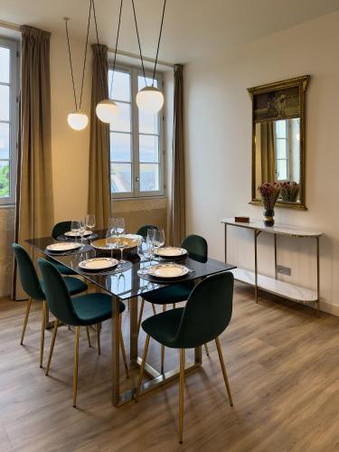 une salle à manger avec une table noire et des chaises vertes dans l'établissement Appartement Saint-Cyr - Les Suites du Palais, parking privé, vue cathédrale, 3 chambres, by PRIMO C0NCIERGERIE, à Nevers