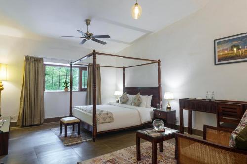a bedroom with a canopy bed and a living room at amã Stays & Trails Bliss Dhauj ,Haryana in Faridabad