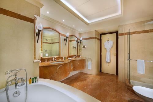a bathroom with a tub and a sink and a mirror at Habtoor Metropolitan Palace Hotel in Beirut