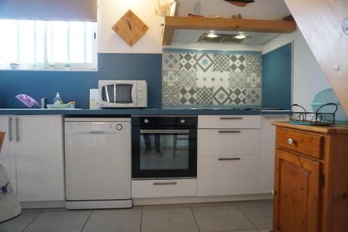 une cuisine avec des armoires blanches et un micro-ondes dans l'établissement La Casote du Pêcheur Bord d'étang 9 Personnes Clim, au Barcarès