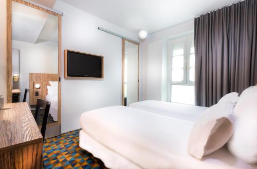 a hotel room with two beds and a television at Libertel Gare Du Nord Suede in Paris