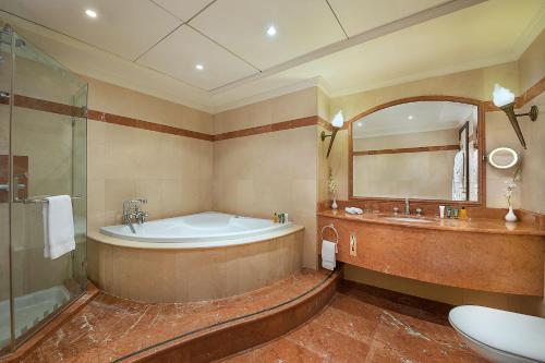 a bathroom with a tub and a sink and a mirror at Habtoor Metropolitan Palace Hotel in Beirut