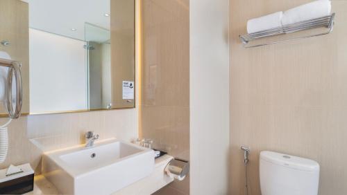 a bathroom with a sink and a toilet and a mirror at Swiss-Belexpress Yogyakarta in Demangan