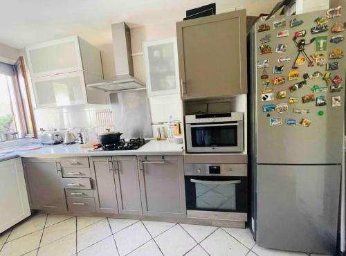 a kitchen with a refrigerator with magnets on it at Cozy villa in Aulnay-sous-Bois