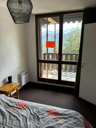 Un dormitorio con una cama y una ventana con vistas. en T2 Praloup 1500, en Uvernet