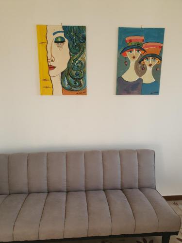 a couch in a living room with two paintings on the wall at Dc apartment in Santa Maria Capua Vetere