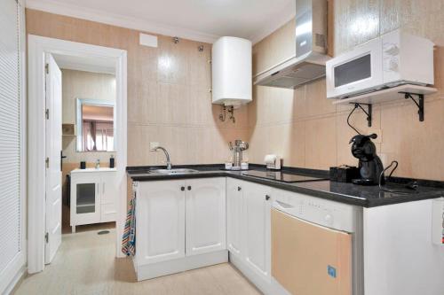 une cuisine avec un évier et un micro-ondes dans l'établissement Estudio con wifi piscina y parking en Benalmádena - ACUARIO 5, à Benalmádena