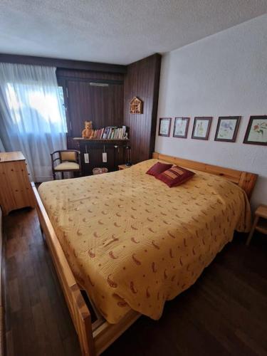 une chambre avec un grand lit avec un couvre-lit jaune dans l'établissement Grazioso appartamento vicino alle piste, à Montgenèvre