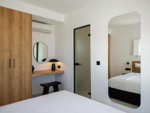 a bedroom with a white bed and a mirror at Blue Eye Grand Villa Mykonos in Kalafatis