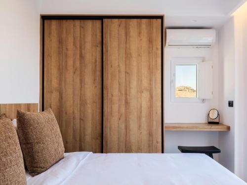 a bedroom with a wooden door and a bed at Blue Eye Grand Villa Mykonos in Kalafatis