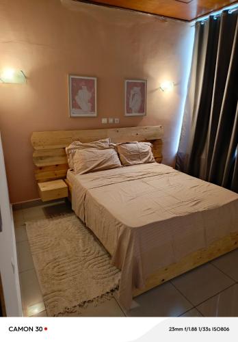 une chambre avec un lit avec une tête de lit en bois dans l'établissement Aphrodite appart, à Pointe-Noire