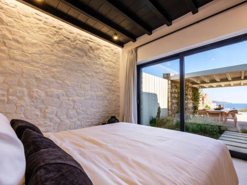 a bedroom with a bed and a large window at Blue Eye Grand Villa Mykonos in Kalafatis