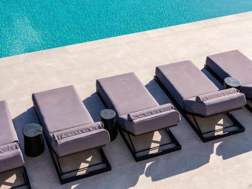 a group of chairs next to a swimming pool at Blue Eye Grand Villa Mykonos in Kalafatis