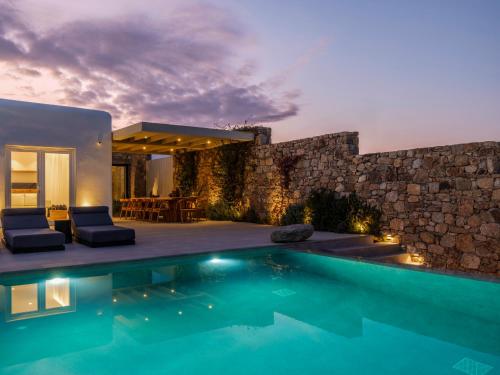a villa with a swimming pool and a stone wall at Blue Eye Grand Villa Mykonos in Kalafatis