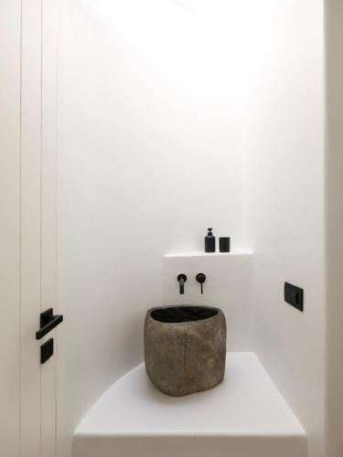 a bathroom with a stone sink on a white wall at Blue Eye Grand Villa Mykonos in Kalafatis
