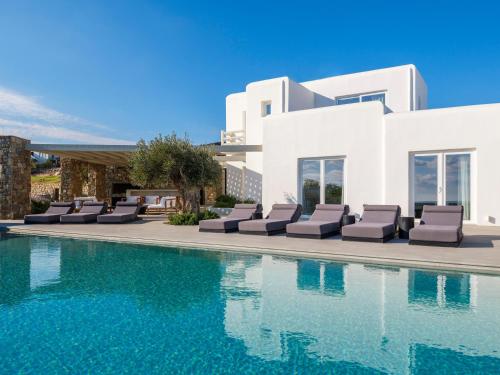 a villa with a swimming pool and lounge chairs at Blue Eye Grand Villa Mykonos in Kalafatis