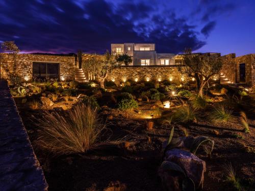 a building with lights in a garden at night at Blue Eye Grand Villa Mykonos in Kalafatis