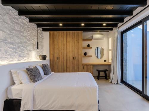 a bedroom with a white bed and a large window at Blue Eye Grand Villa Mykonos in Kalafatis