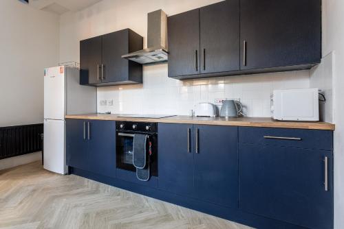 a kitchen with blue cabinets and a white refrigerator at Impressive 6-BR Home in a Prime Sunderland in Sunderland