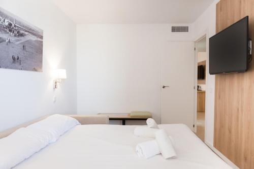 a white bedroom with a white bed and a flat screen tv at Ibersol Siurell in Sa Coma