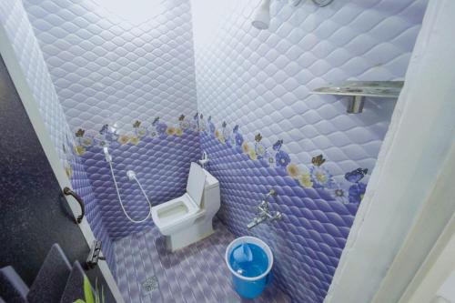 a purple tiled bathroom with a toilet and a sink at Sai Guest House in Tiruvannāmalai