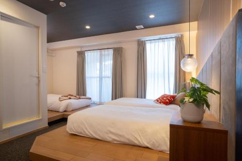 a bedroom with two beds and a potted plant at WAYFARER Kyoto Shijo in Kyoto