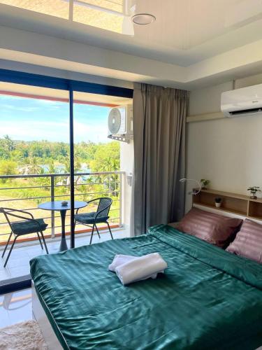 a bedroom with a large green bed and a balcony at Cozy Room Phuket in Ban Mai Salae