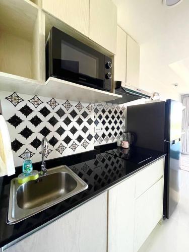 a kitchen with a sink and a black refrigerator at Cozy Room Phuket in Ban Mai Salae