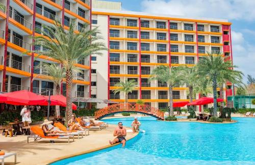 a pool at a resort with people sitting on chairs and a bridge at Cozy Room Phuket in Ban Mai Salae