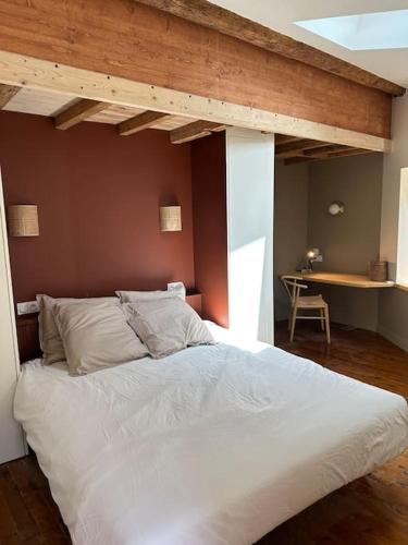 Cette chambre comprend un grand lit blanc et une table. dans l'établissement Charmante maison de ville à 10' du centre de Lyon, à Sainte-Foy-lès-Lyon