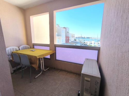 une table et des chaises dans une pièce avec une fenêtre dans l'établissement 023 DESIRADES A11, au Cap d'Agde
