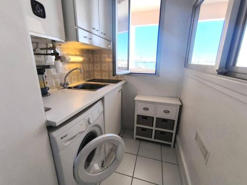 une petite cuisine avec une machine à laver et un évier dans l'établissement 023 DESIRADES A11, au Cap d'Agde