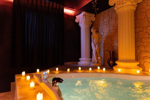 a bath tub with candles and columns in a room at La Suite de Vénus - Chambre à thème Love Room Jacuzzi et Pièce Secrète - Évasion pour deux in Schirrhein