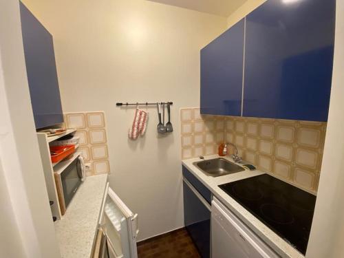 Elle comprend une petite cuisine avec un évier et des placards bleus. dans l'établissement Appartement accès direct plage, à Arcachon