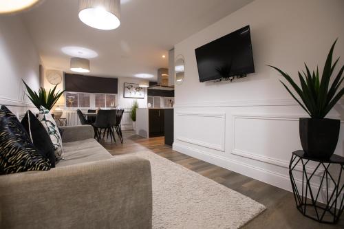 a living room with a couch and a tv on the wall at The Burlington Collection in Sheringham