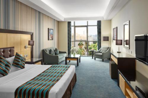 um quarto de hotel com uma cama e cadeiras e uma televisão em RAND by Wandalus em Riade