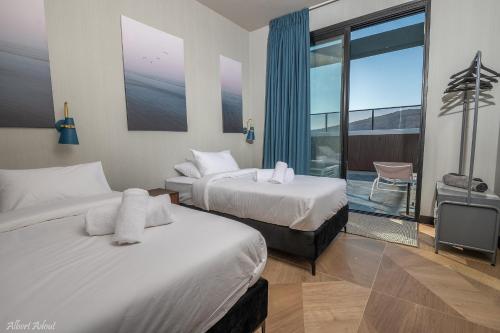 a hotel room with two beds and a balcony at Naomi Boutique Suites in Netu'a
