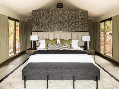 a bedroom with a large bed and two windows at Kunkura Game Lodge & Conference Centre in Modimolle