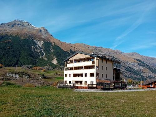 a building in a field with mountains in the background at Terrasses D 406 PARC NAT VANOISE appart 4 pers in Val Cenis
