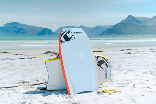 two surfboards sticking out of the sand on a beach at Last Word Long Beach in Kommetjie