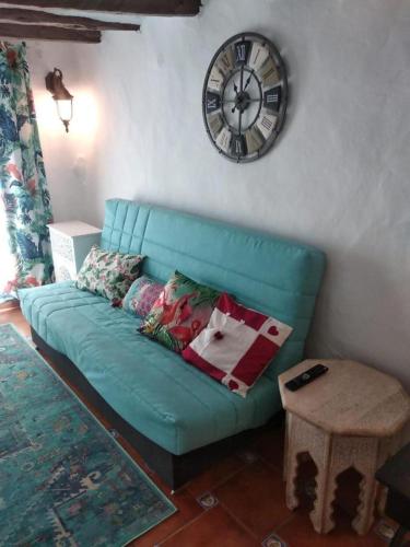 a green couch in a living room with a clock on the wall at La Vía Verde in Jérica