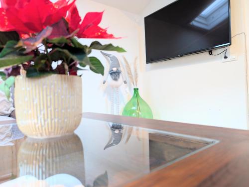 a glass table with a vase with red flowers in it at Neu! Moderner bayrischer Flair vor Pilatushaus in Oberammergau