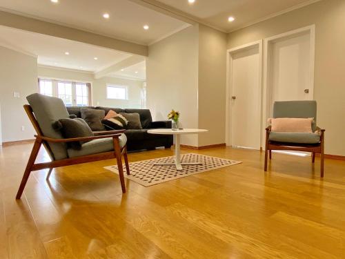 a living room with a couch and a table and chairs at Cosy family house in Massey with Good View in Auckland