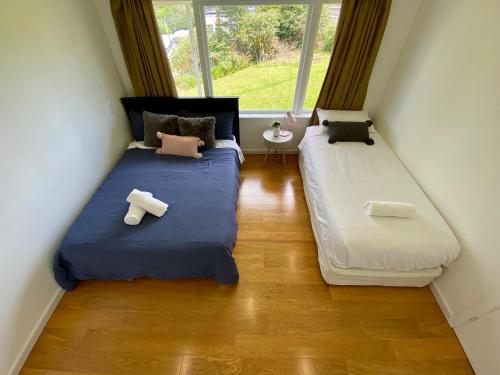 two beds in a small room with two windows at Cosy family house in Massey with Good View in Auckland