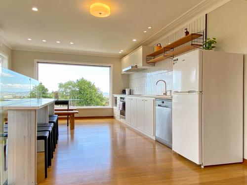 a kitchen with a white refrigerator and a table at Cosy family house in Massey with Good View in Auckland
