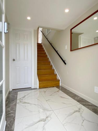 a hallway with white marble floors and a staircase at Cosy family house in Massey with Good View in Auckland