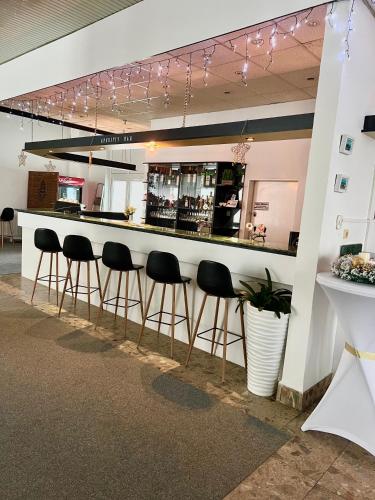a bar with black stools in a room at Hotel Pelikán in Lučenec